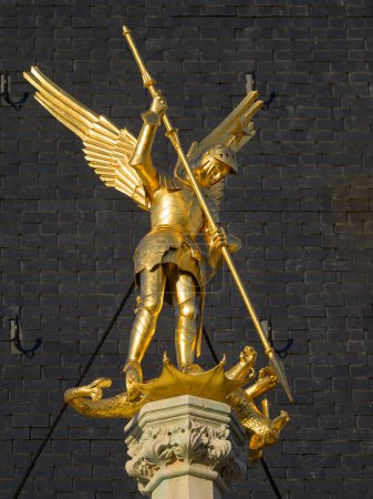 Foto de A golden angel statue killing the evil dragon with a spear, daylight, building, Bruges (Belgium) - Imagen libre de derechos