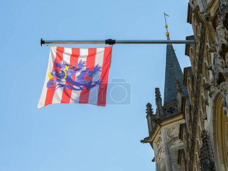 Foto de Bruges, Belgium-July 4, 2022: Flag of Bruges hanging from a house, background, blue sky - Imagen libre de derechos
