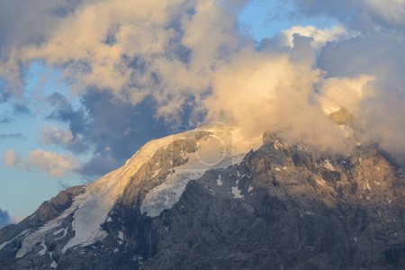 The Ortler Alps near Stelvo Pass at sunset in summer, clouds around the peak
