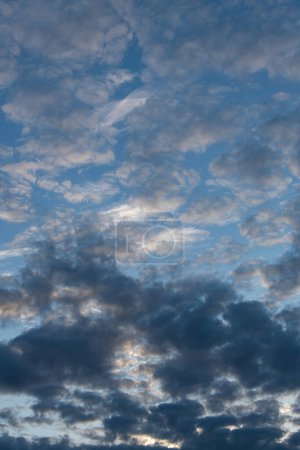 A vertical photograph with contrasting light gray and dark gray clouds filling almost the entire blue sky in the photograph