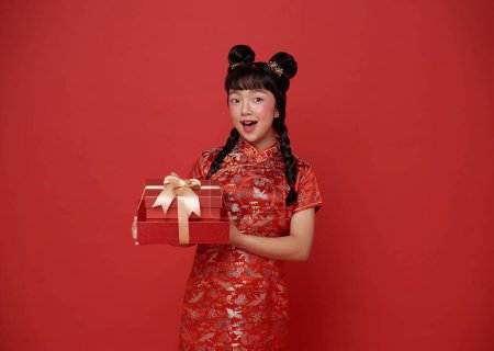 Photo for Happy smiling children asian girl in red traditional costume giving gift box for bless chinese new year 2024 isolated on red background. - Royalty Free Image