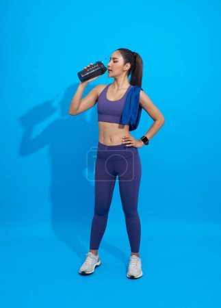 Téléchargez les photos : Asiatique Sporty jeune femme boire shake protéine isolé sur fond bleu. - en image libre de droit
