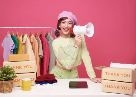 Young asian woman startup small business freelance seller clothing holding megaphone announce promotion sell isolated on pink background, Online marketing and delivery concept