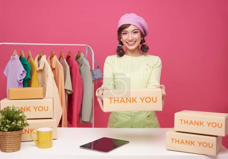 Young asian woman startup small business freelance seller clothing with parcel box and tablet computer on table isolated on pink background, Online marketing and delivery concept