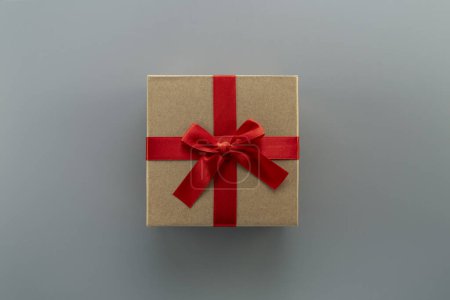 Foto de Caja de regalo con cinta roja primer plano sobre fondo gris, vista superior - Imagen libre de derechos
