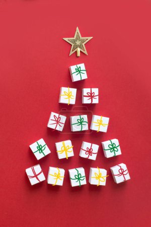 Téléchargez les photos : Forme abstraite arbre de Noël par plusieurs boîtes-cadeaux sur fond rouge. - en image libre de droit