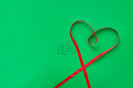 Photo for Heart shape red ribbon on green background. - Royalty Free Image