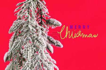 Téléchargez les photos : Carte de voeux de Noël. joyeux Noël lettrage sur fond rouge avec arbre de Noël enneigé - en image libre de droit