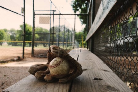 Foto de Primer plano tiro de guante de béisbol de cuero en banco de madera en campo dugout - Imagen libre de derechos