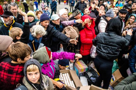 Foto de Los residentes de Kherson, Ucrania, reciben suministros de alimentos en Freedom Square. La tensión es muy fuerte y la gente está muy exasperada. La ayuda humanitaria internacional se organiza cuando la gente carece de todo. - Imagen libre de derechos