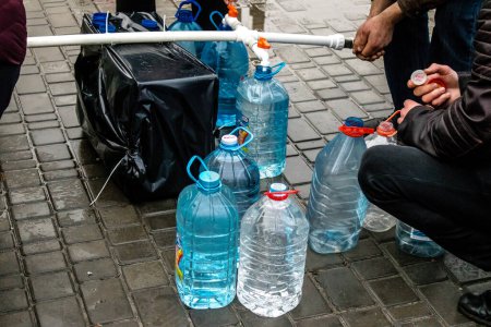 Photo for Residents of Kherson in Ukraine, collecting drinkable water at Freedom Square. International humanitarian aid is organized when people lack everything. The Russian army has bombed the infrastructure of the city and the water supply is completely cut - Royalty Free Image