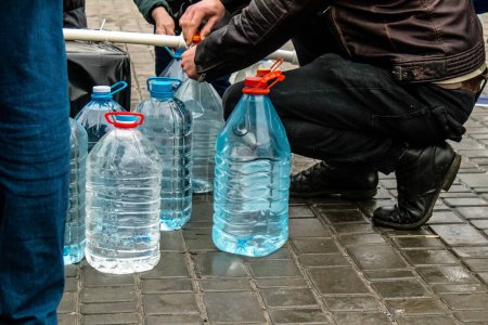 Foto de Residentes de Kherson en Ucrania, recogiendo agua potable en Freedom Square. La ayuda humanitaria internacional se organiza cuando la gente carece de todo. El ejército ruso ha bombardeado la infraestructura de la ciudad y el suministro de agua está completamente cortado. - Imagen libre de derechos