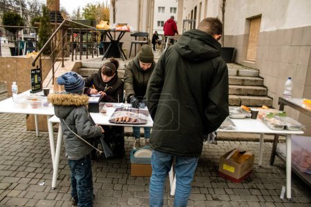Téléchargez les photos : Un restaurateur ouvre une cuisine de rue sur la place principale de Kherson. Il cuisine de la viande avec un feu de bois bien qu'il n'y ait pas d'électricité ou d'eau que les gens s'organisent pour vivre normalement - en image libre de droit