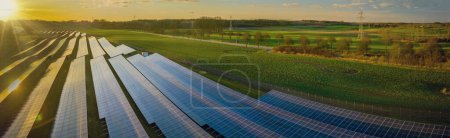 Photo for Photovoltaic panels on open spaces. The solar park along highway. View of a solar power station, Renewable green energy. Alternative energy sources. Clean energy industry. - Royalty Free Image