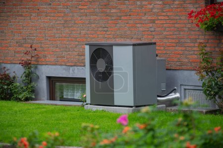 Air heat pump installed on the exterior facade of the old house. Sustainable heating solutions for old construction. Air source heat pump beside residential country cottage.