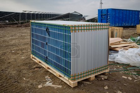 Pallets containing solar modules and components for solar panels at the construction site of a photovoltaic park. Solar panels stacked on pallets for installation and construction waste in background.