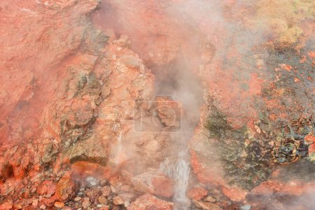 Geothermal hot springs with steam, colorful mineral deposits and living moss on rocks. Location: Deildartunguhver, the Largest Hot Springs in Europe.