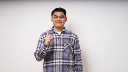 Photo for Young Asian man showing happy face expression while giving one fingers sign - Royalty Free Image