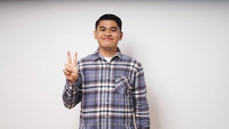 Foto de Joven asiático hombre mostrando feliz cara expresión mientras dando dos dedos signo - Imagen libre de derechos