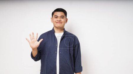 Photo for Young Asian man showing happy face expression while giving five fingers sign - Royalty Free Image
