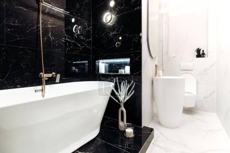 Photo for Modern marble bathroom with freestanding bathtub beside a fancy sink and toilet - Royalty Free Image