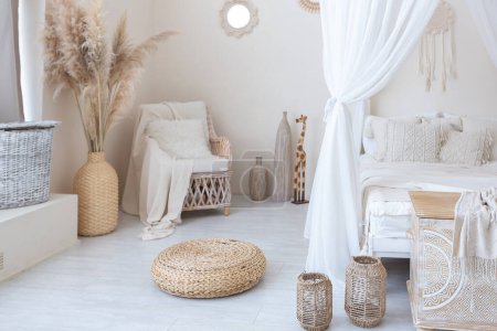 Photo for Daylight through a huge panoramic window illuminates the cozy oriental interior of the room in beige colors with wicker furniture and authentic elements - Royalty Free Image