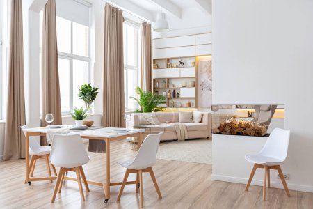 Inneneinrichtung geräumige helle Studio-Wohnung im skandinavischen Stil und warmen Pastellweiß und Beige-Farben. Trendmöbel im Wohnbereich und moderne Details im Küchenbereich.