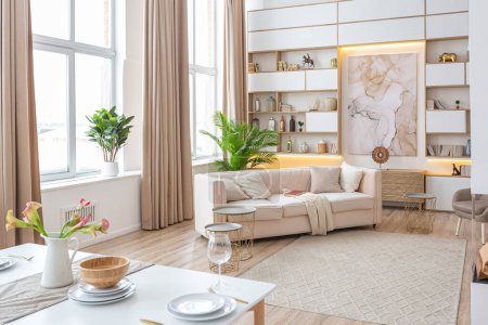 Photo for Interior design spacious bright studio apartment in Scandinavian style and warm pastel white and beige colors. trendy furniture in the living area and modern details in the kitchen area. - Royalty Free Image