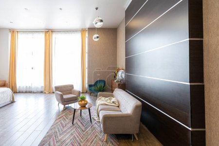 Diseño ordinario contemporáneo de estudio espacioso en suaves colores cálidos. Muebles simples. Habitación grande con luz solar. Durante el día. Azulejos de piso marrón y paredes blancas .