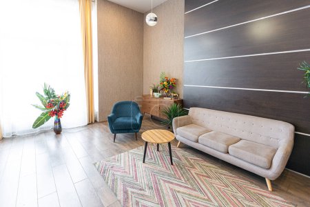Diseño ordinario contemporáneo de estudio espacioso en suaves colores cálidos. Muebles simples. Habitación grande con luz solar. Durante el día. Azulejos de piso marrón y paredes blancas .