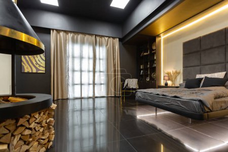 Téléchargez les photos : Sombre moderne élégant appartement masculin intérieur avec éclairage, murs décoratifs, cheminée, dressing et grande fenêtre - en image libre de droit