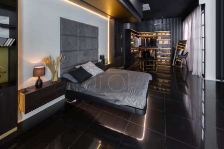 Foto de Oscuro moderno elegante apartamento masculino interior con iluminación, paredes decorativas, chimenea, vestidor y ventana enorme - Imagen libre de derechos
