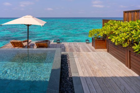 Lujoso exterior de una villa rica en agua muy cara en las Maldivas, decorada con madera natural.