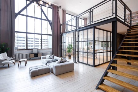 Photo for Trendy modern design two-level apartment with large high windows. The stylish living room and kitchen in bright colors are undressed by a glass partition. bedroom on the second floor. - Royalty Free Image