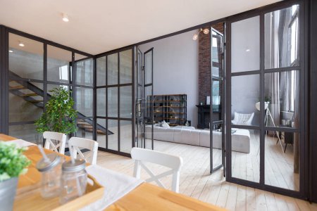 trendy modern design two-level apartment with large high windows. The stylish living room and kitchen in bright colors are undressed by a glass partition. bedroom on the second floor.
