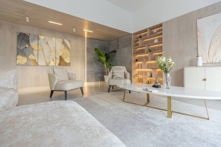 Téléchargez les photos : Design intérieur moderne de la salle de séjour dans le studio dans des couleurs douces chaudes. éclairage intégré décoratif et mobilier beige doux - en image libre de droit