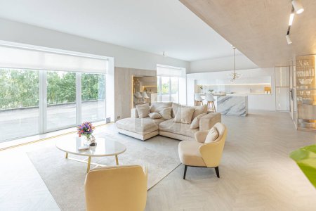 design intérieur moderne à la mode d'un grand studio aux couleurs blanc et beige avec de grandes baies vitrées. zone de cuisine blanche avec un îlot et une zone de loisirs