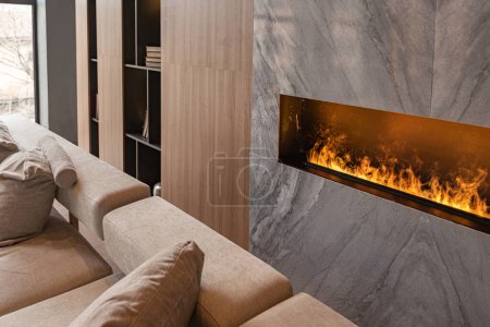 Photo for Living room, marble wall fireplace and stylish bookcase in chic expensive interior of luxury country house with a modern design with wood and led light, gray furniture with gold elements - Royalty Free Image