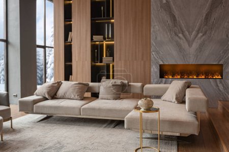 salon, cheminée murale en marbre et bibliothèque élégante dans un intérieur chic et coûteux de maison de campagne de luxe avec un design moderne avec du bois et de la lumière led, meubles gris avec des éléments en or