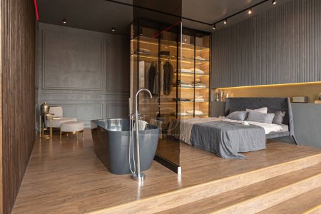 outstanding bath and bedroom of a chic modern design of a dark expensive interior of a luxurious country house with huge panoramic windows and a magnificent view of the divine forest