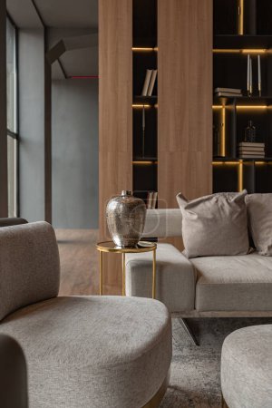 Wohnzimmer, Wandkamin aus Marmor und stilvolles Bücherregal im schicken teuren Interieur eines luxuriösen Landhauses mit modernem Design mit Holz und LED-Licht, graue Möbel mit Goldelementen