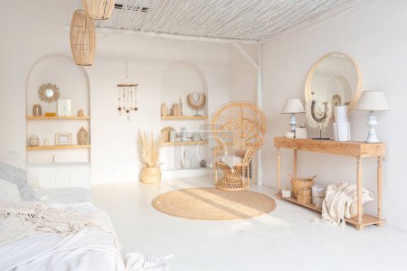 Téléchargez les photos : Intérieur confortable d'un appartement lumineux de style balinais avec murs blancs, chaise en bambou, grand canapé blanc et décorations - en image libre de droit