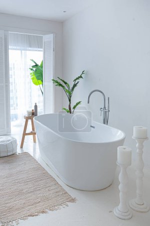 Extra blanc et très léger minimaliste élégant intérieur élégant de salle de bain avec baignoire moderne, plantes vertes et éléments en bois