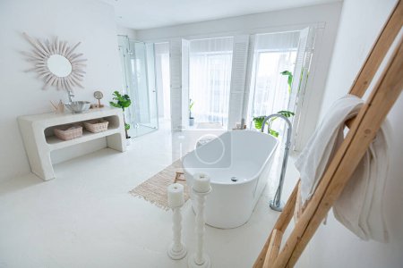 Téléchargez les photos : Extra blanc et très léger minimaliste élégant intérieur élégant de salle de bain avec baignoire moderne, plantes vertes et éléments en bois - en image libre de droit