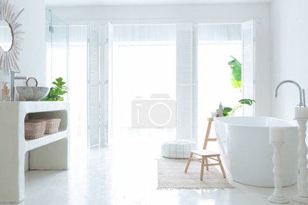 Extra blanc et très léger minimaliste élégant intérieur élégant de salle de bain avec baignoire moderne, plantes vertes et éléments en bois