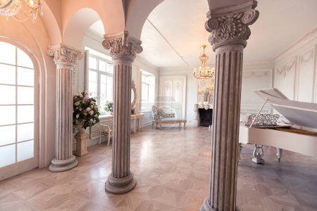 Luxuriöse helle Einrichtung des Wohnzimmers im Barockstil wie in einem königlichen Schloss mit alten stilvollen Vintage-Möbeln, Säulen, Stuck an den Wänden