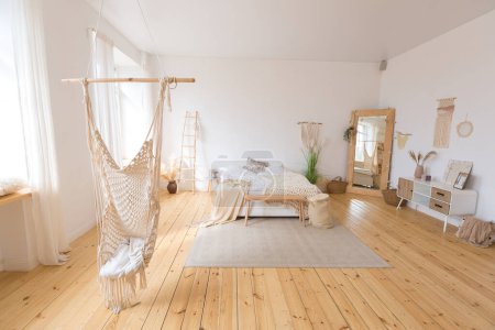 Photo for Cute cozy light interior design of the apartment with a free layout of the kitchen and bedroom areas. a lot of windows, a wooden floor and a hanging swing. - Royalty Free Image