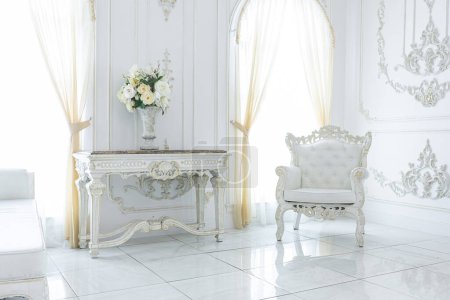 Téléchargez les photos : Luxueux intérieur royal chic dans un style baroque. hall très lumineux, lumineux et blanc avec meubles de style ancien coûteux. grandes fenêtres et décorations en stuc sur les murs - en image libre de droit
