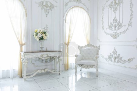 interior elegante real de lujo en estilo barroco. vestíbulo muy luminoso, ligero y blanco con muebles de estilo antiguo caros. grandes ventanas y adornos de estuco en las paredes
