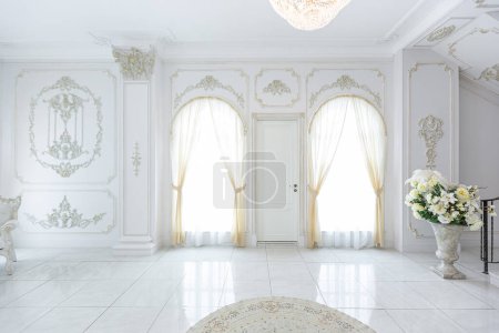 luxueux intérieur royal chic dans un style baroque. hall très lumineux, lumineux et blanc avec meubles de style ancien coûteux. grandes fenêtres et décorations en stuc sur les murs